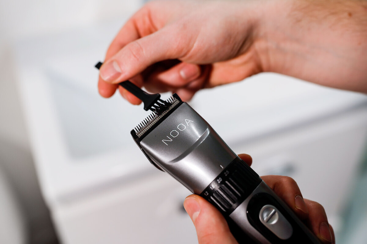 Man cleaning the hair clipper with included brush