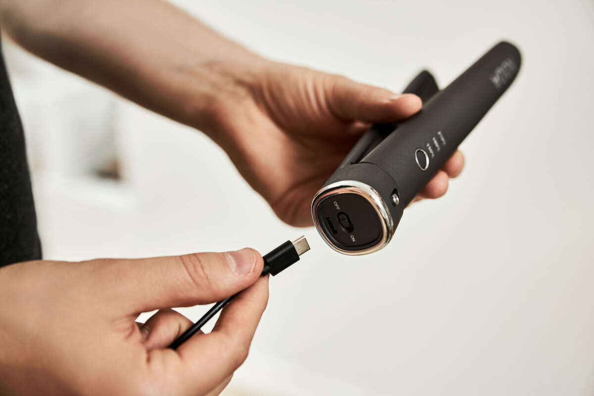 A close-up picture of a person putting a USB C cable to a NOOA hair straightener