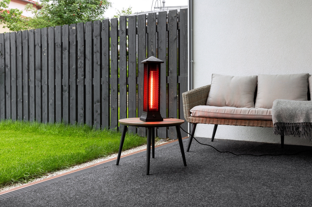 POINT PRO POPHTOW53 PATIO HEATER outdoors on a table, with green grass on the right and a comfy grey sofa on the background