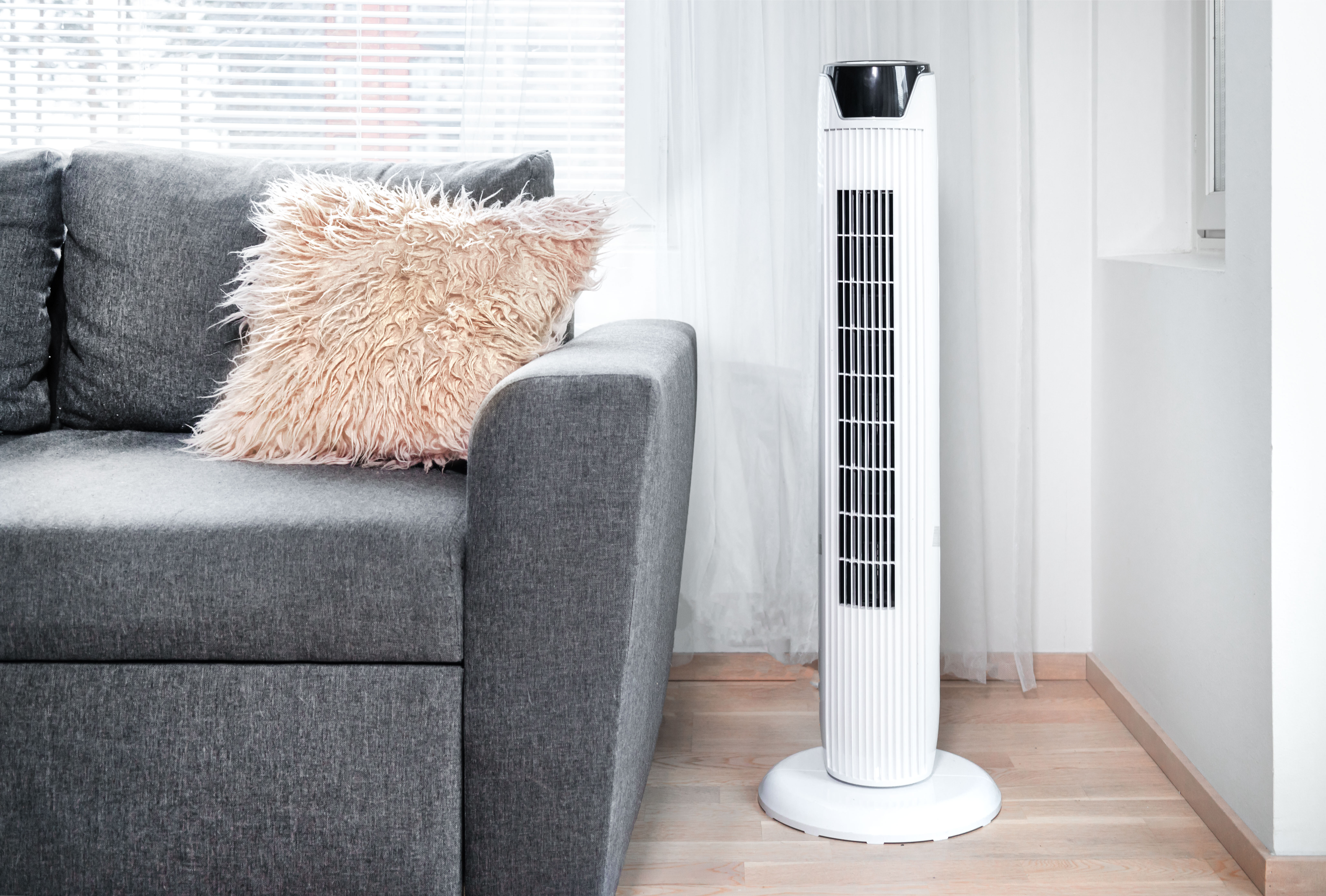 Tower fan on the living room floor next to a sofa