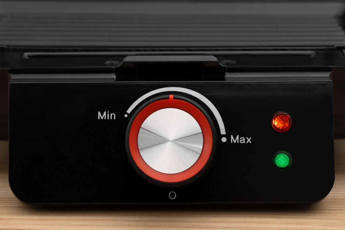 A black Point sandwich grill up close with its silver adjustment knob showing and the red and green ready-lights on
