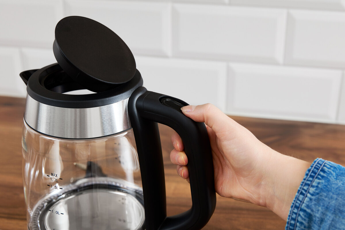 Person pressing the opening button of the kettle