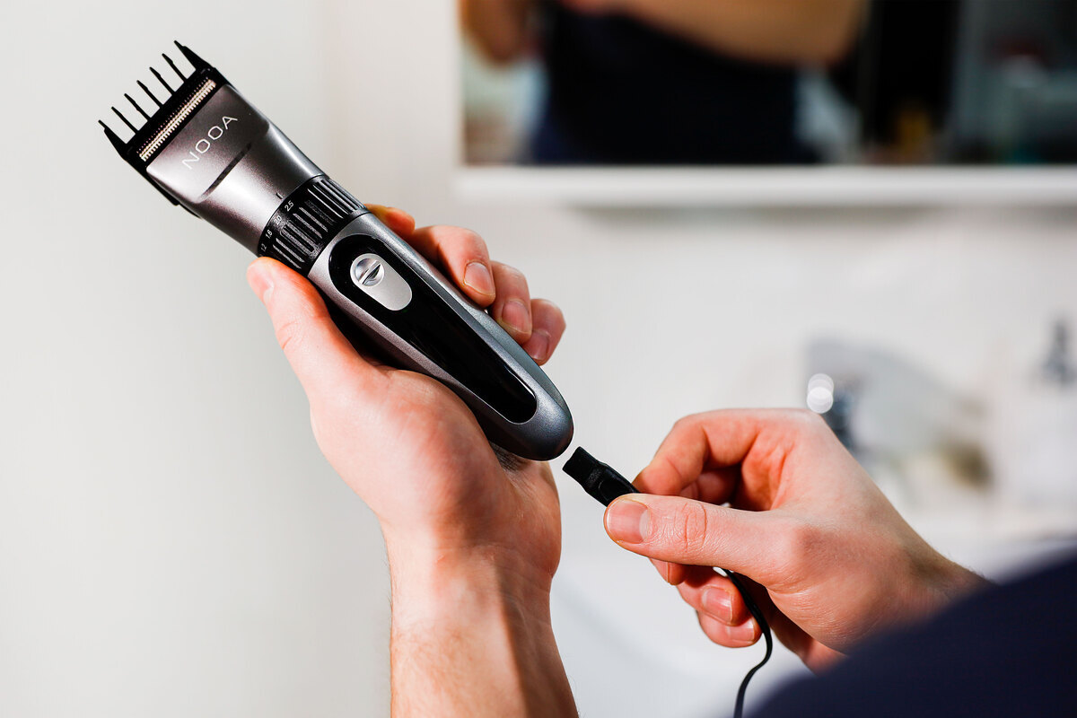 Man attaching the charging cable to the hair clipper