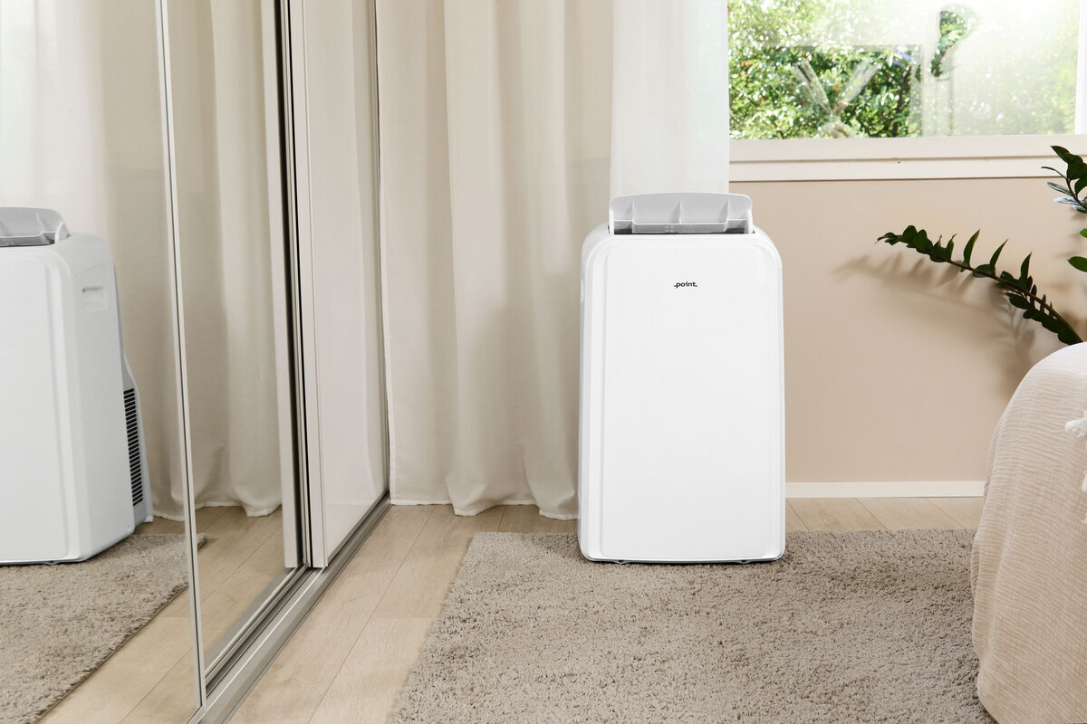 The POINT PRO POAC8014 air conditioner in front of a beige wall with a mirror wardrobe door on the left