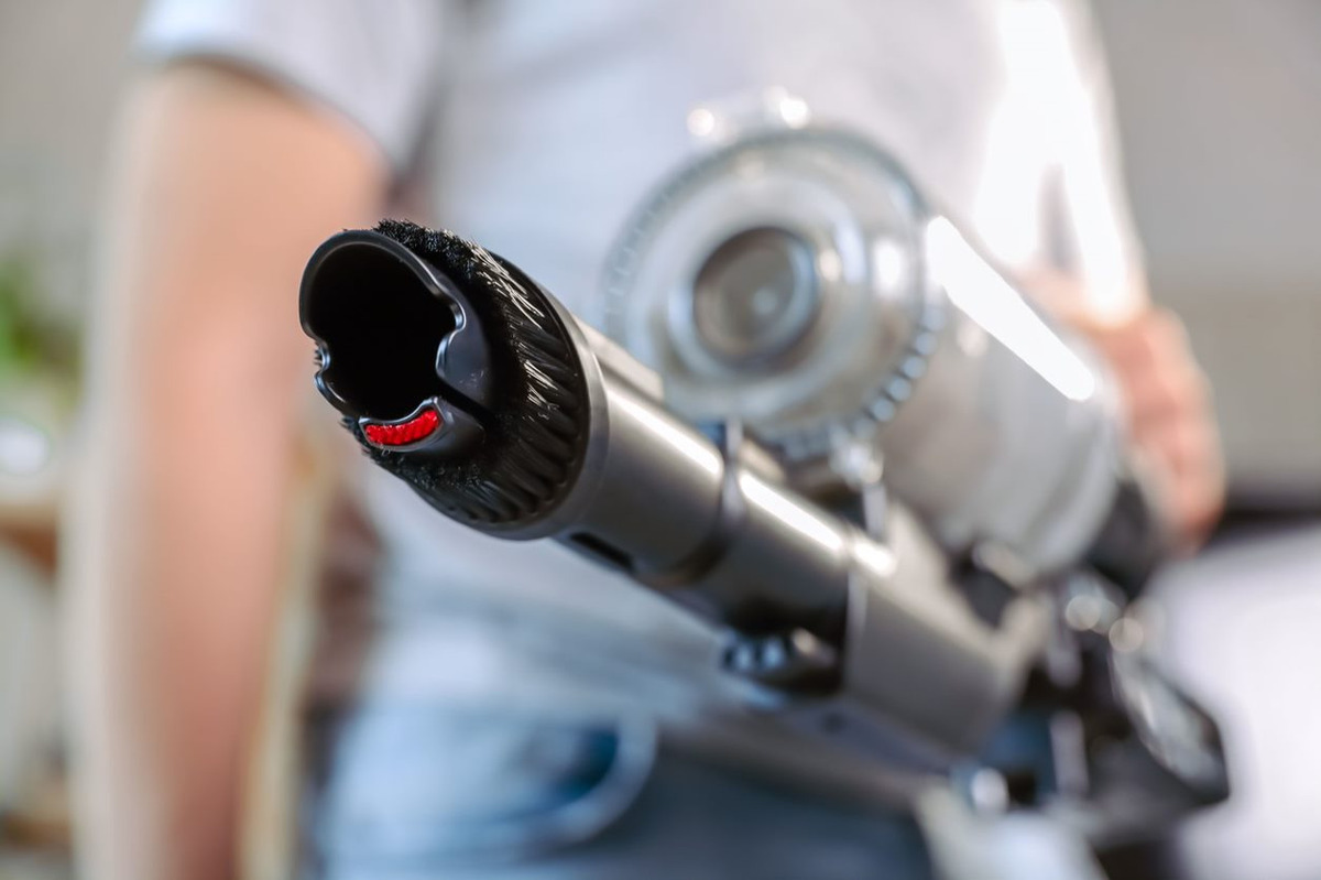 Close up of the combination nozzle of the POINT POVC618DB 18V stick vacuum, person with grey t-shirt and blue jeans holding it