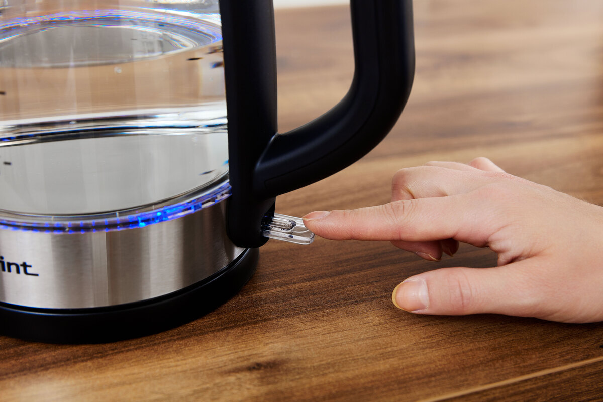 Person pressing the on/off switch of the kettle and led lights are illuminated