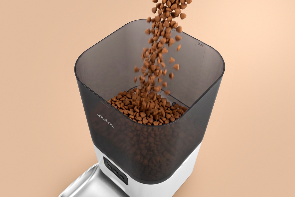 The Point Pet Feed smart feeder pictured from above with the food storage showing and dry food being poured inside