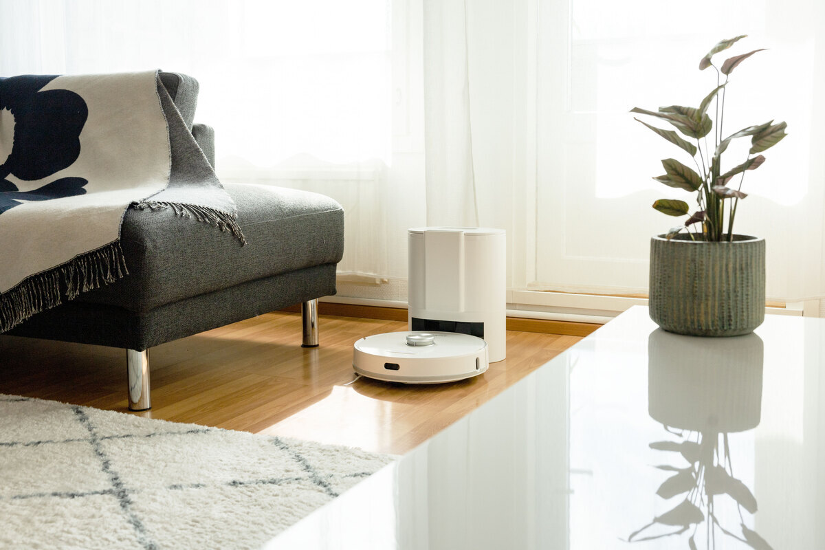 Robot vacuum and the emptying station in the living room next to a sofa