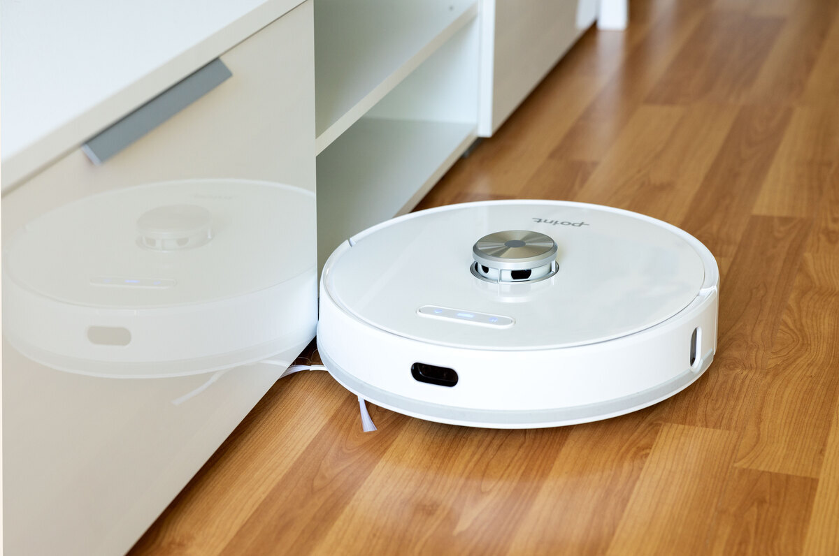Robot vacuum vacuuming the floor next to a tv stand