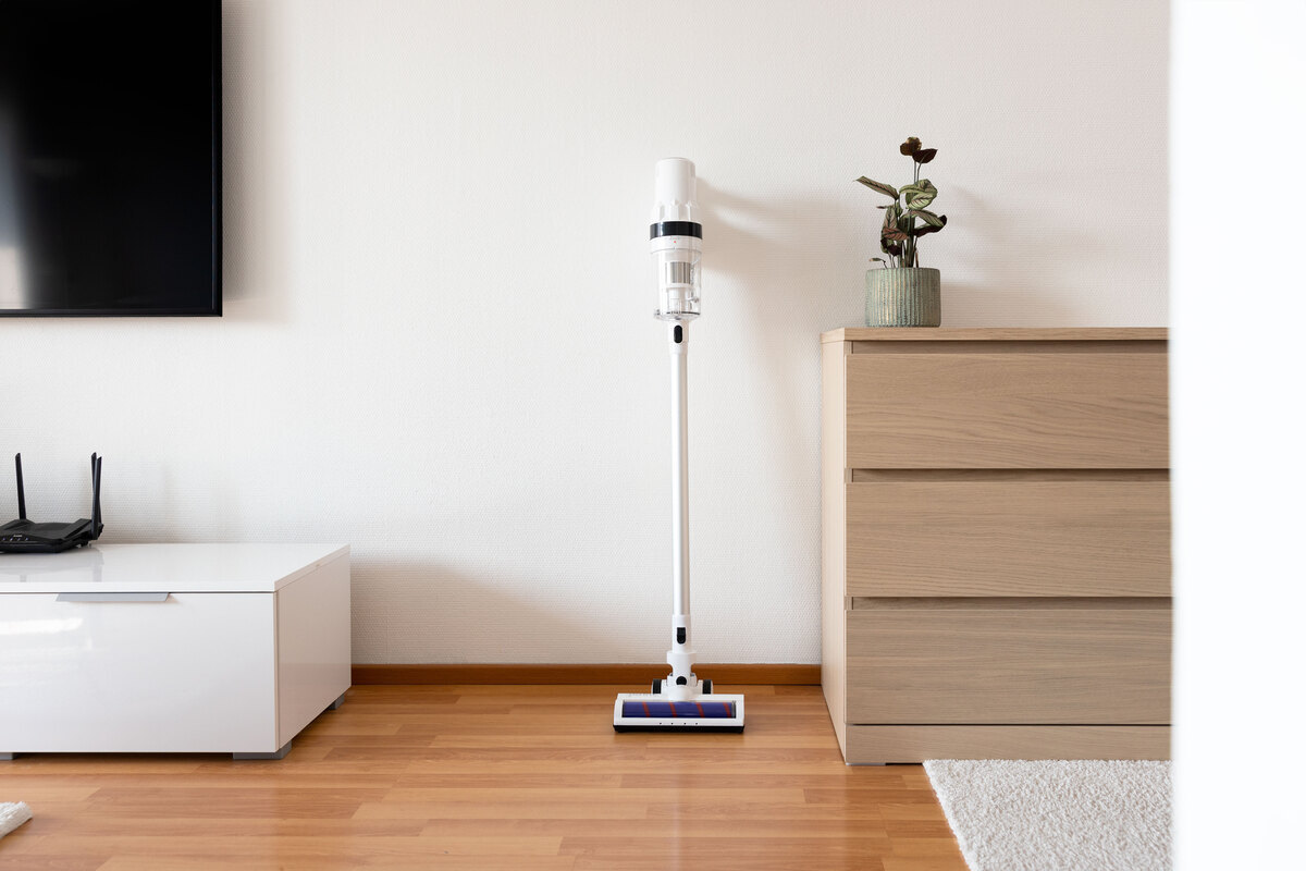 Point stick vacuum cleaner against a living room wall next to a wooden drawer