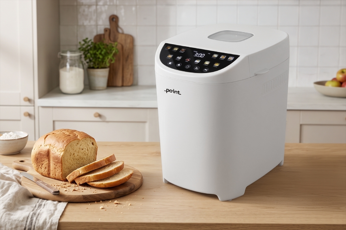 POINT POBM5000 BREADMAKER A white Point breadmaker on a wooden kitchen counter in a slightly tilted position with sliced bread next to it on the table and a bright kitchen behind the machine