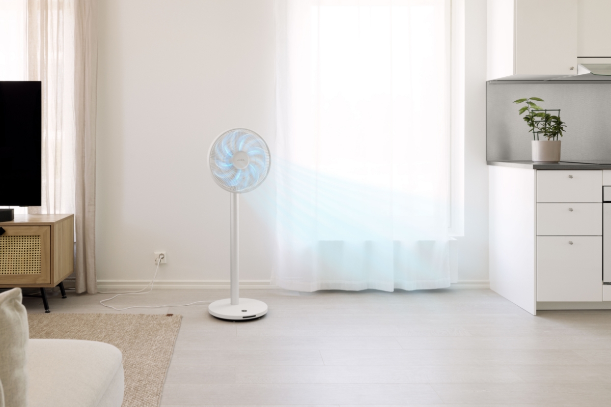 Wide angle image of the POINT POFS16ALU 16" DC SILENT STAND FAN standing between open plan kitchen and living room, blue arrows indicating cold air