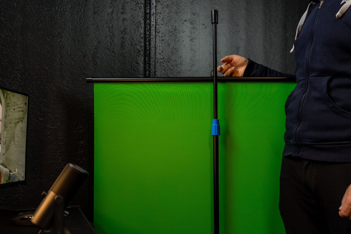 Person adjusting the height of a green screen