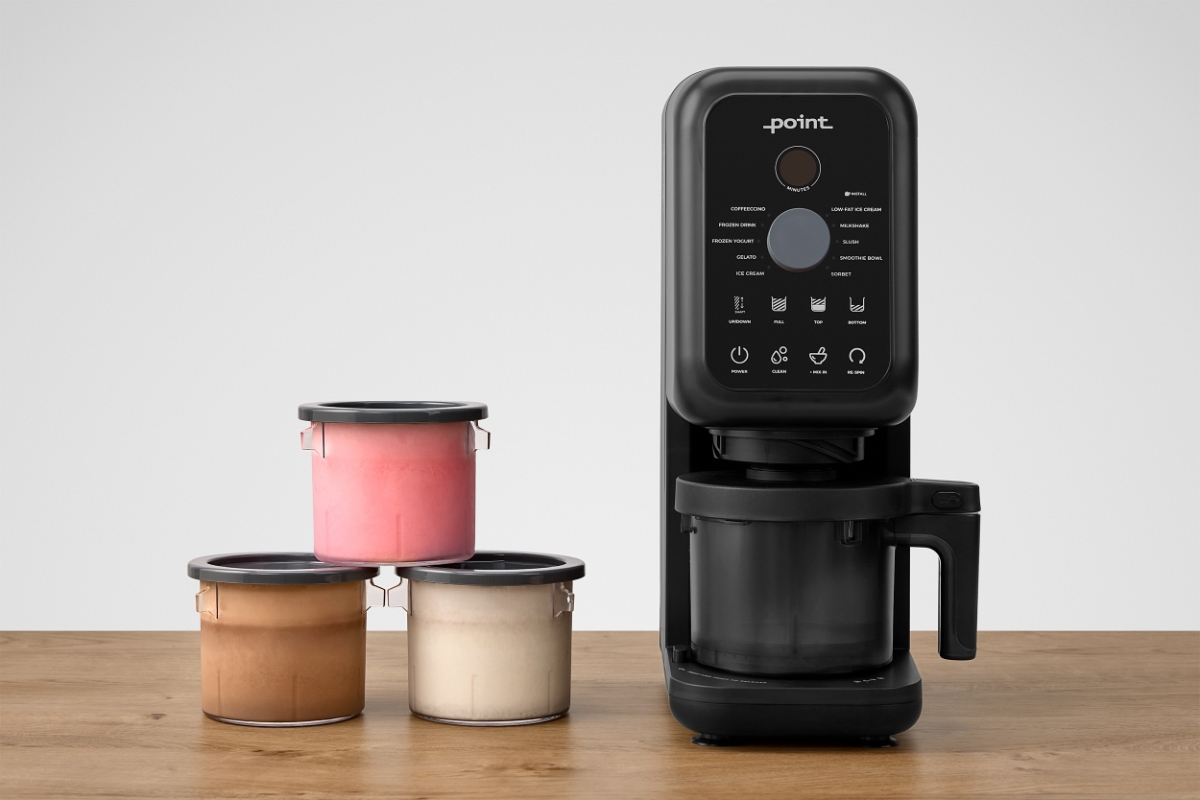 A black Point ice cream machine on a wooden table with three cups filled with ice cream next to it on the table in a pyramid form