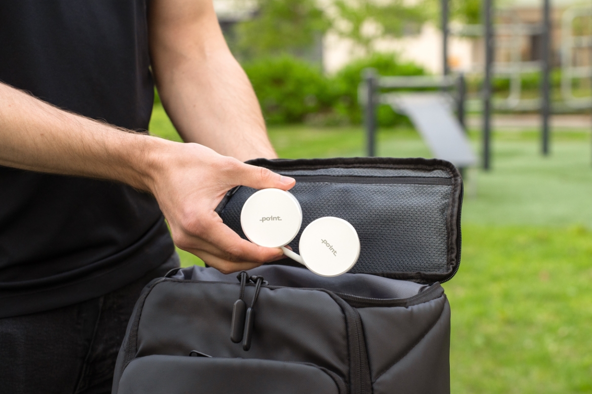 POINT NECK FAN WH White Point neck fan rolled in a compact size and a man in a black shirt putting the fan in his workout bag outside in a green park