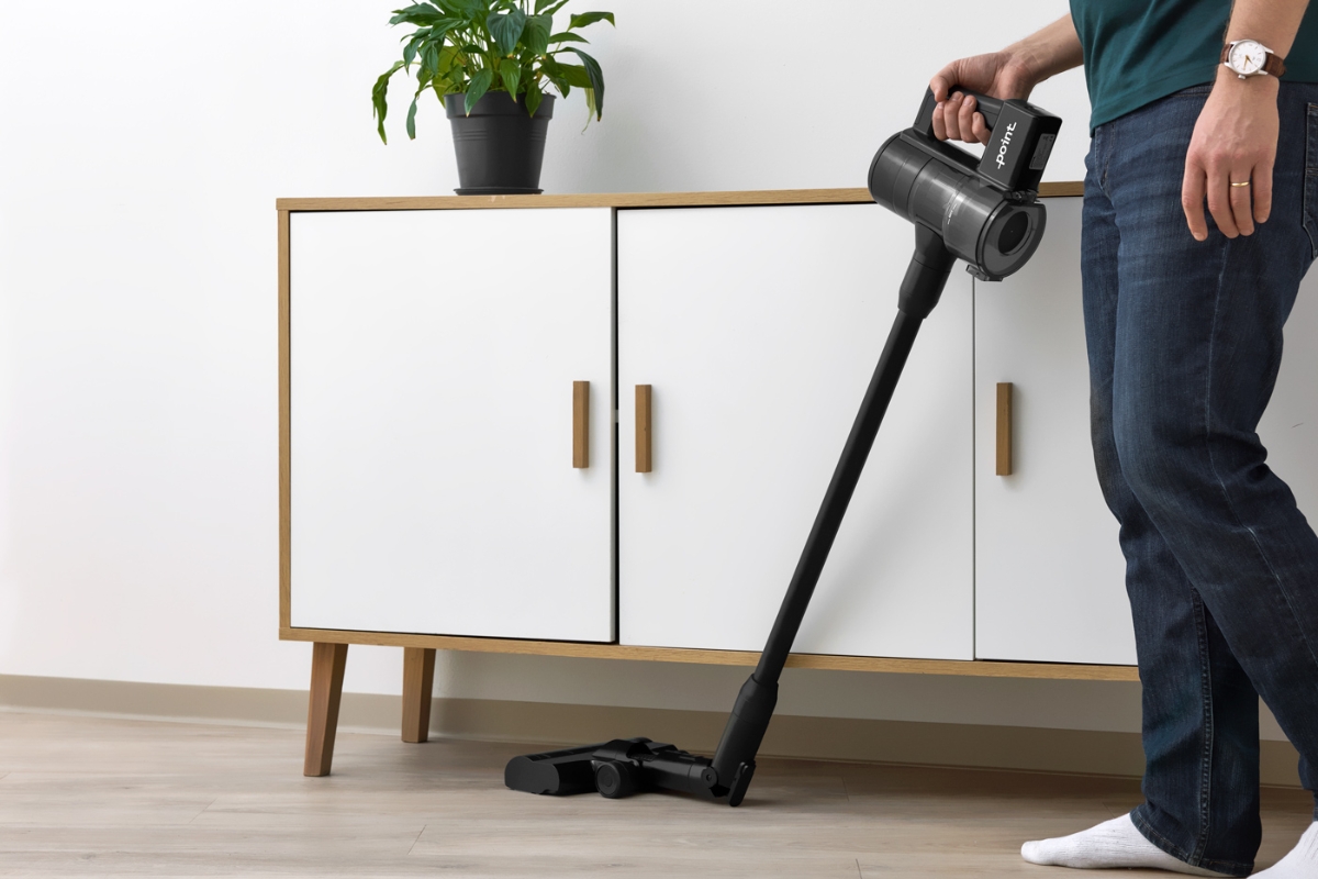Wide angle image of POINT PENCIL+ CORDLESS VACUUM CLEANER vacuuming under a white side table