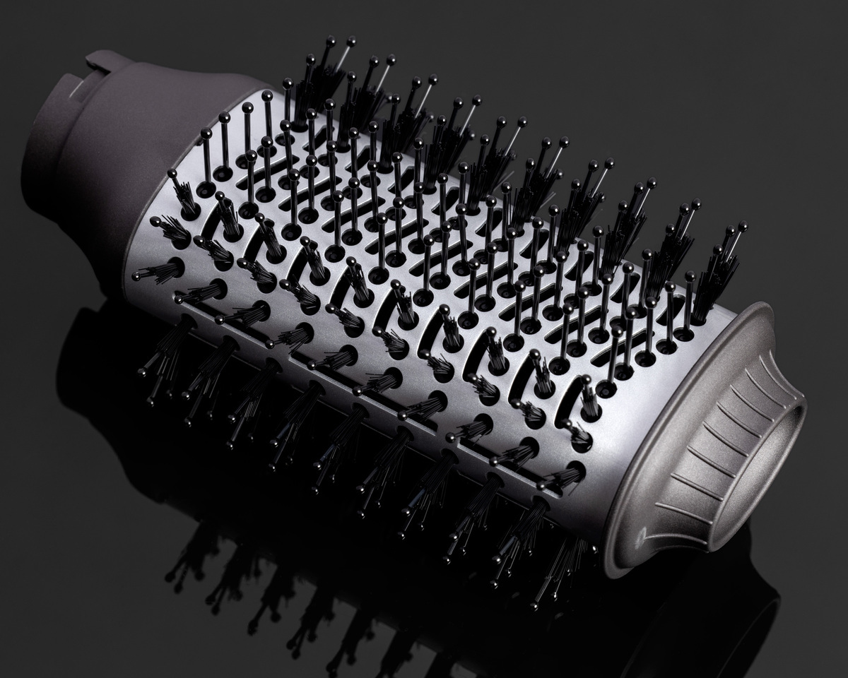 A close-up picture of NOOA hot air brush's big brush with black bristles placed on a black shiny table with a shadow of the air brush