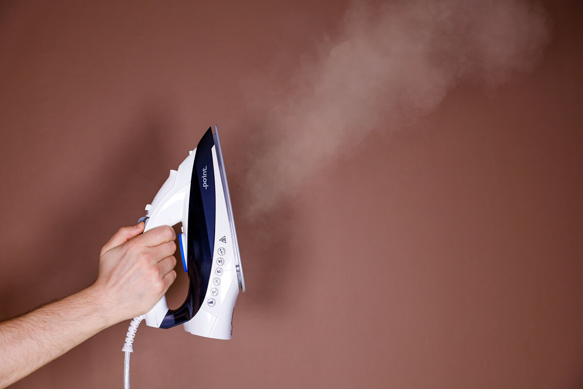 Person pressing the steam button of the iron