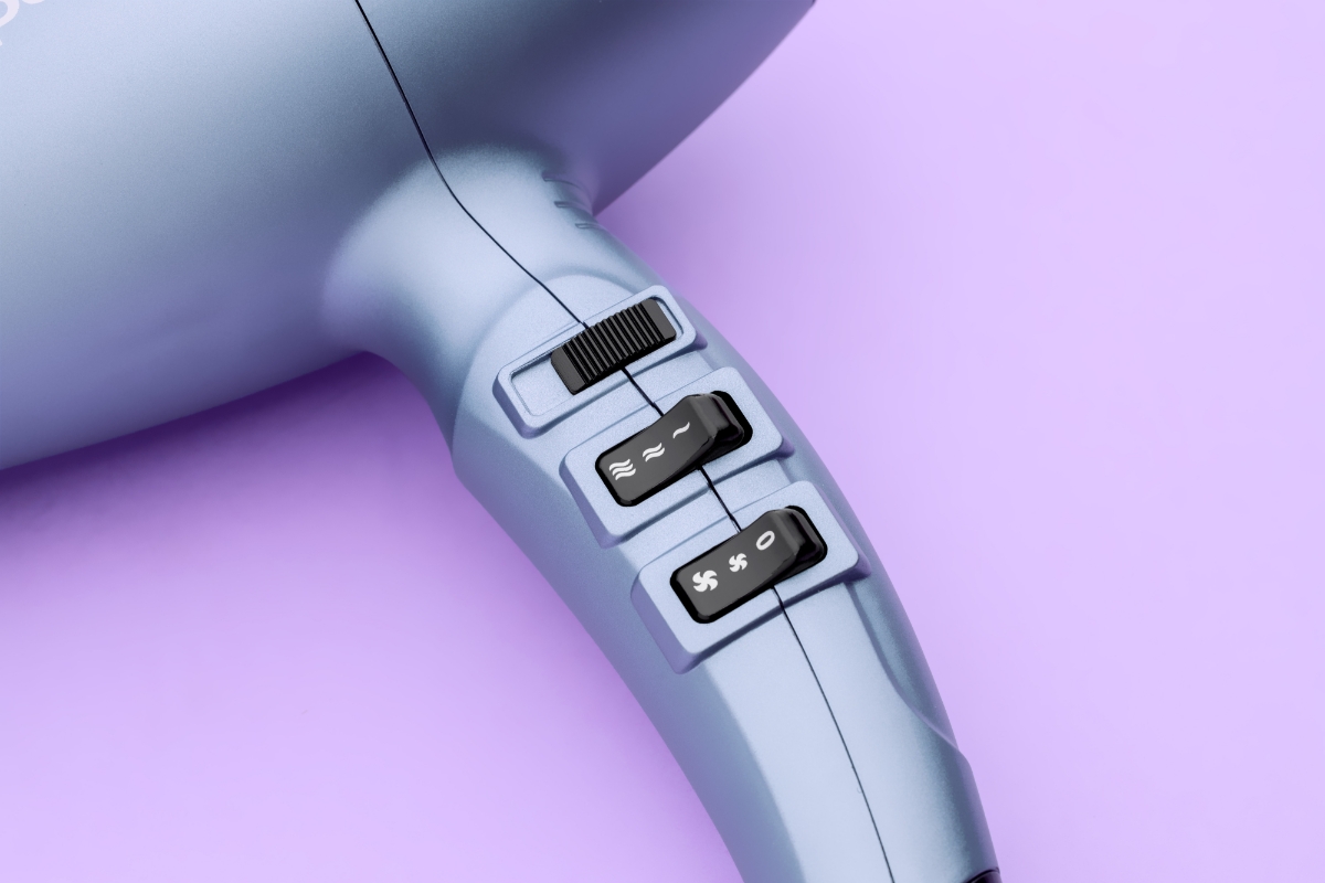 Close up of the adjustment buttons of the POINT POHD897AC RADIANT BLOW HAIR DRYER against a purple background