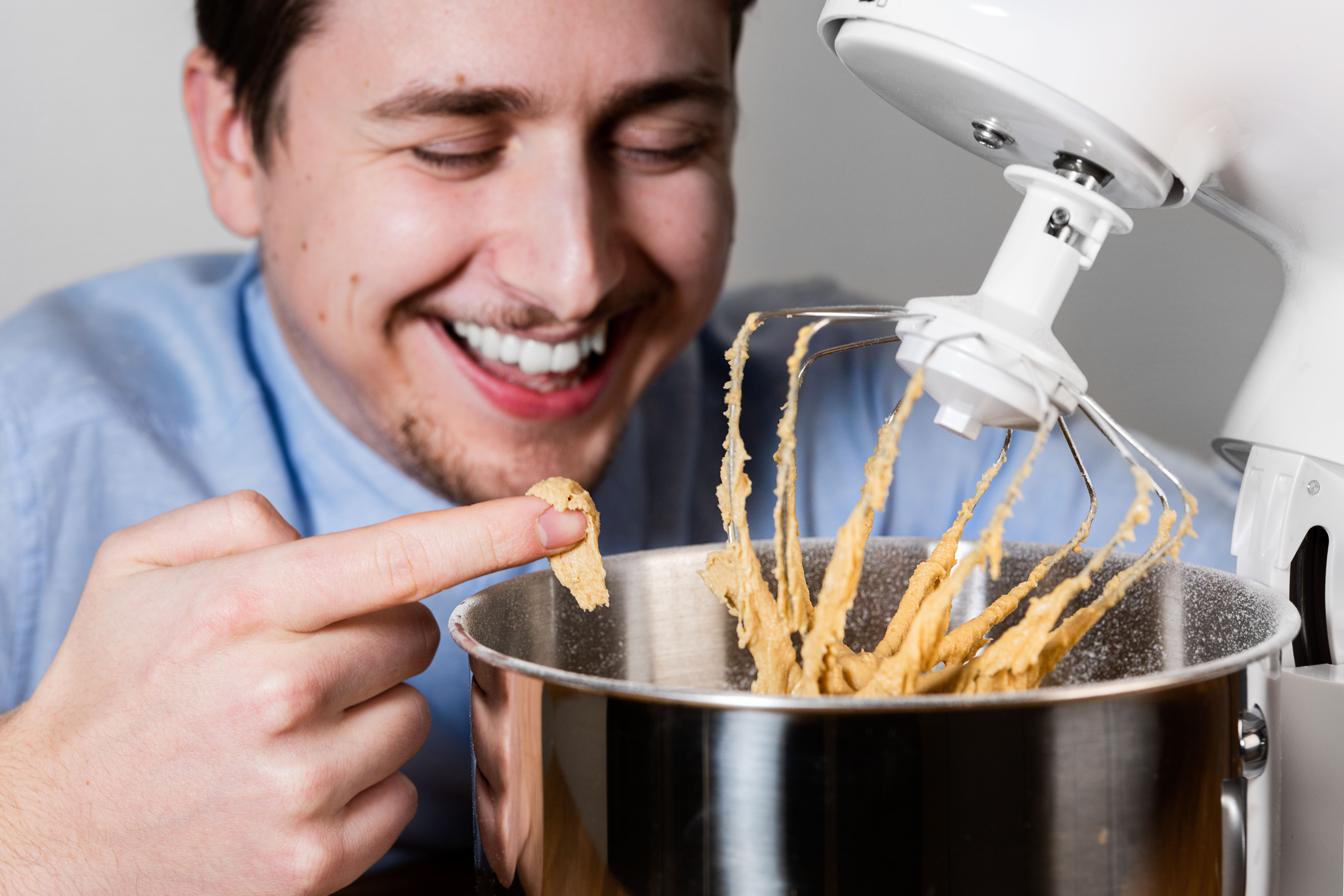 A white stand mixer with dough and man laughing