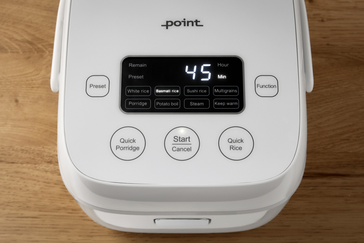 A white Point rice cooker on a wooden table with the image taken from a bird view and the LED display of the machine showing clearly