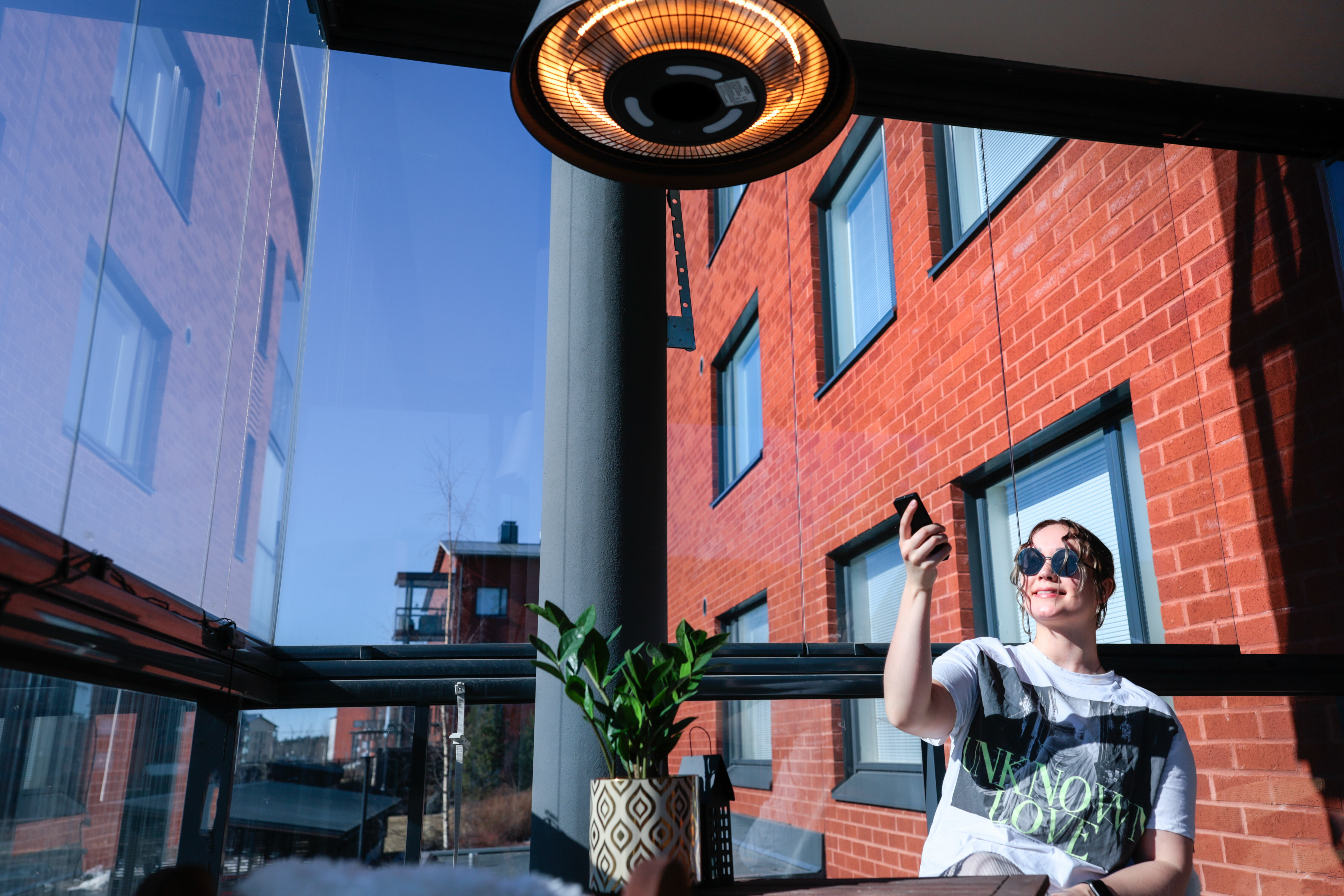 Woman adjusting patio heater with remote control on a balcony