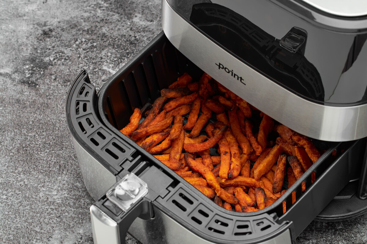 Close up of the airfryer basked full of sweetpotato fries on the grey surfase