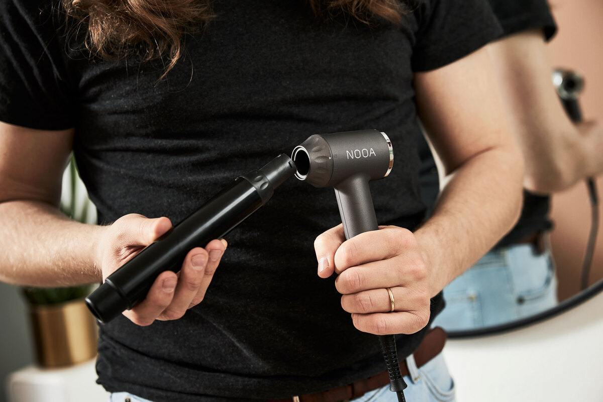 A close up of a person wearing a black t-shirt attaching a curling barrel onto the Nooa Divine multi curler