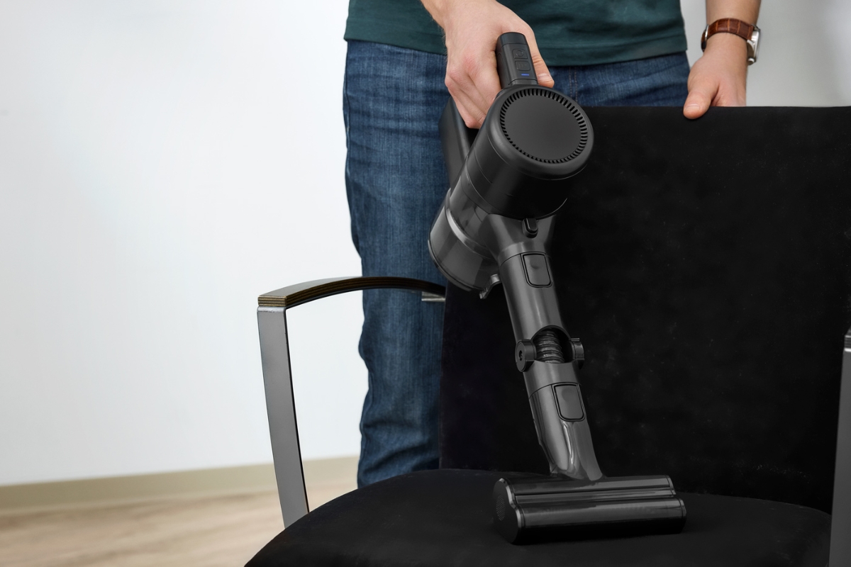 The handheld vacuum of POINT PENCIL+ CORDLESS VACUUM CLEANER vacuuming an armchair