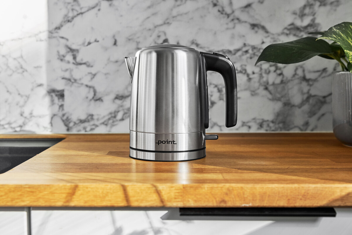 POINT POKE50SS1 kettle on a wooden kitchen worktop with a marble wall behind it and a plant in the right corner
