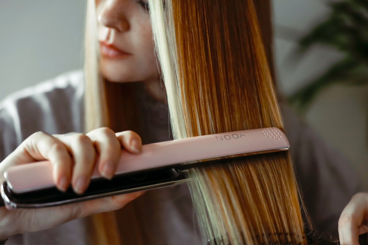 Woman straightening long hair with straightener