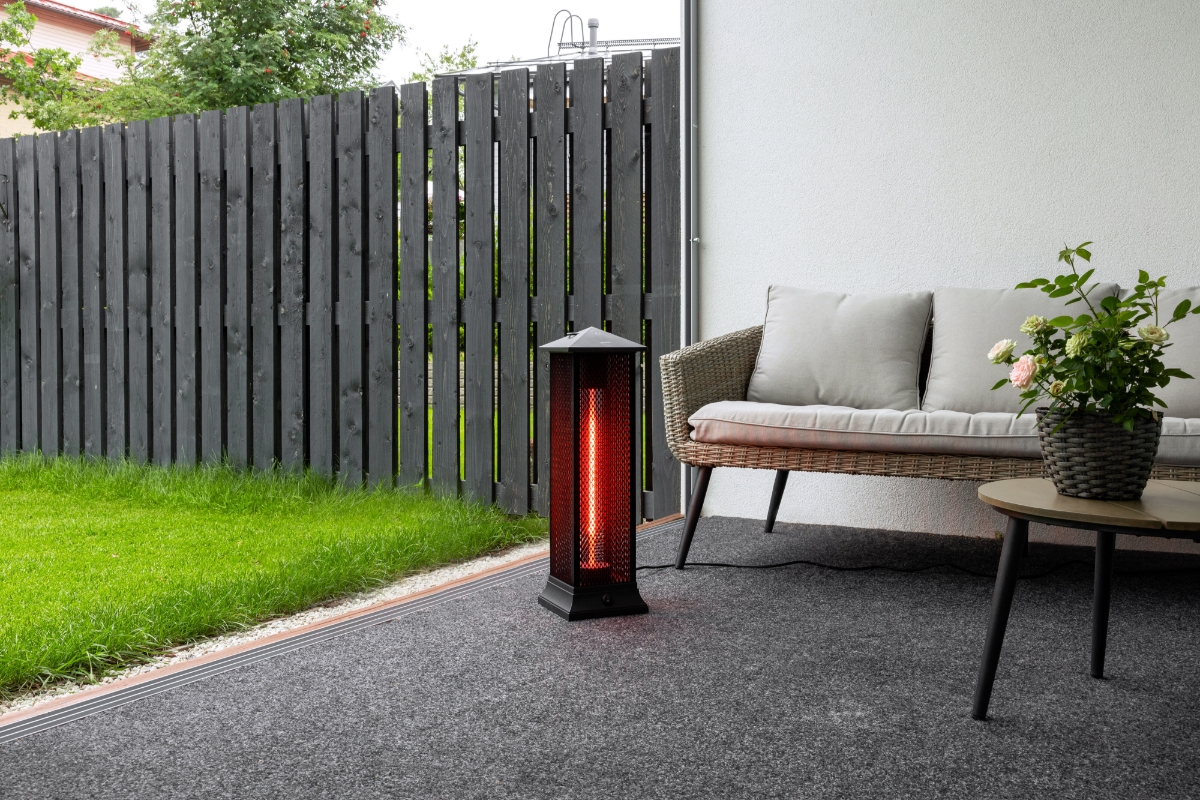 POINT PRO POPHTOW66 PATIO HEATER outside on patio, with green grass to the right and a comfy grey sofa behind the heater