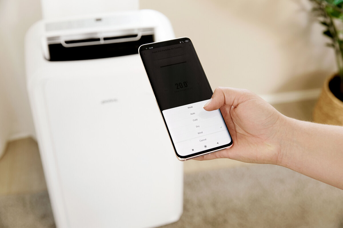 Close up of the smartphone app and person adjusting the functions of the air conditioner and air conditioner on the back ground