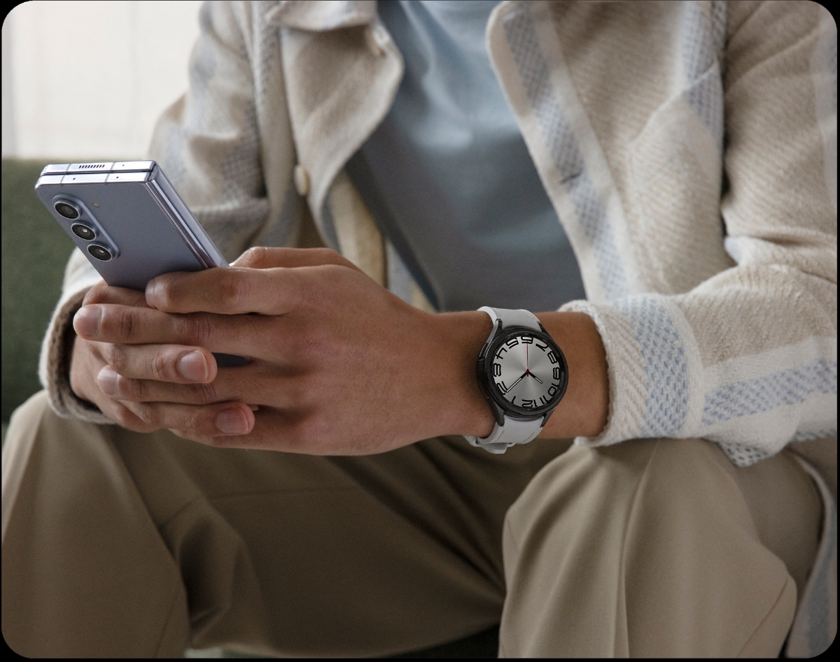 En person som bär en Samsung Galaxy Watch6 Classic och håller i en Samsung Z Fold-telefon