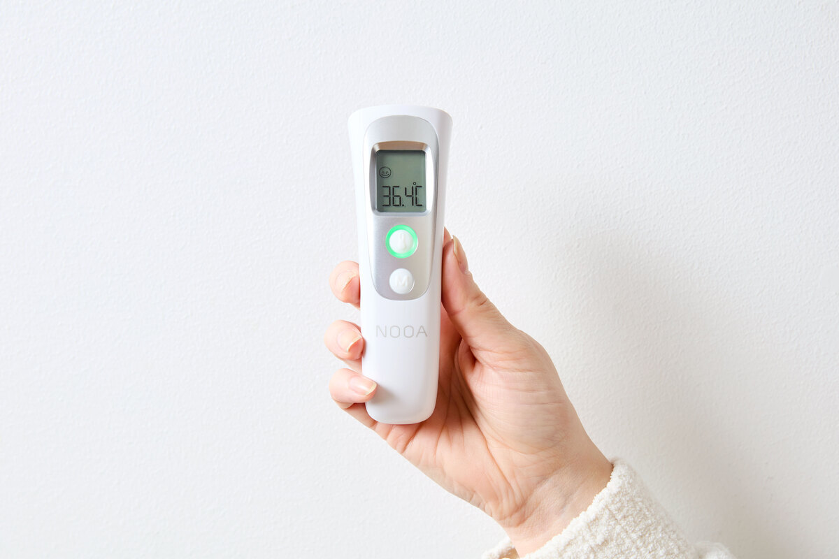 A close-up picture of a Point thermometer in a person's hand against a white background