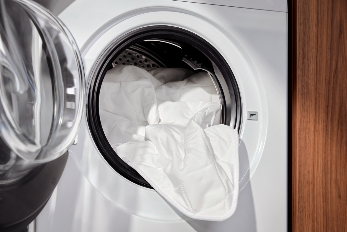 A white Point heated underblanket pushed to a washing machine