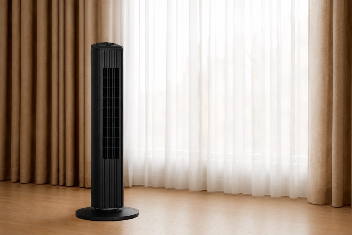 A black Point tower fan in a room with wooden floor and lots of light coming through a big window that has white curtains in front of it