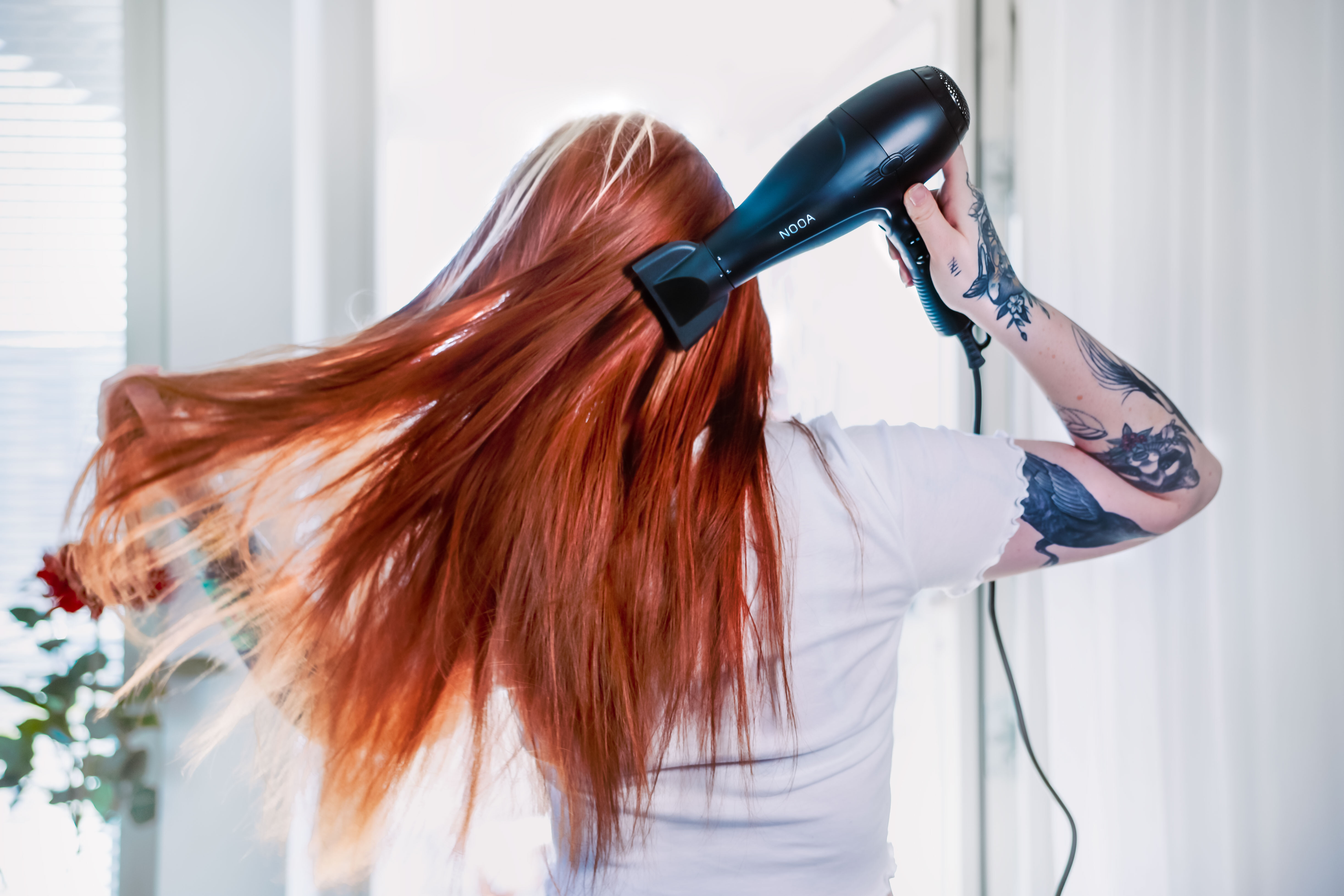 Woman using the hairdryer in front of the balcony door from behind