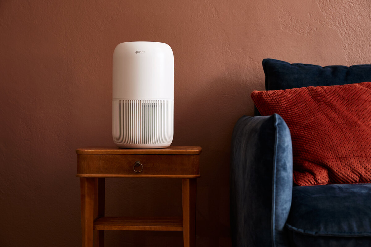 Air purifier on the side table next to a sofa and red wall
