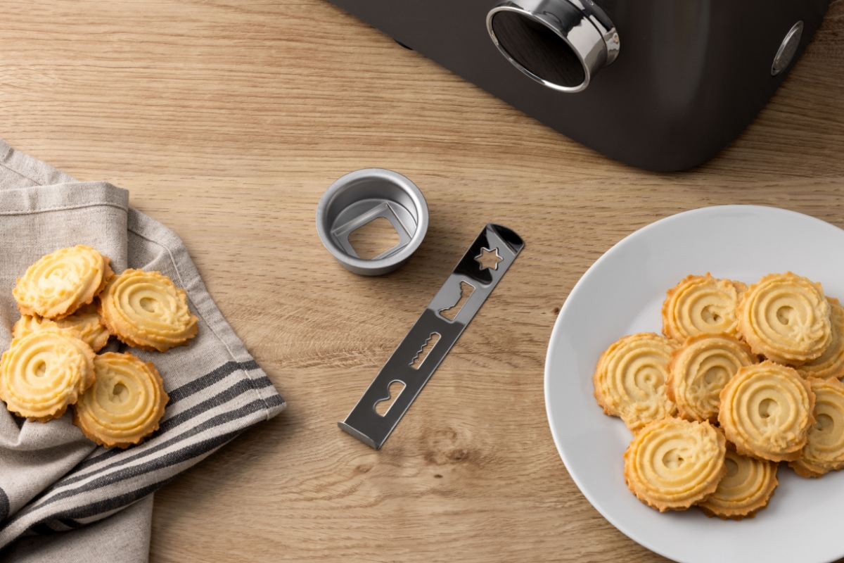 Birds eye view of the cookie cutter attachment of POINT POKM5000 KITCHEN MACHINE 6L/1500W on wooden countertop with cookies next to it