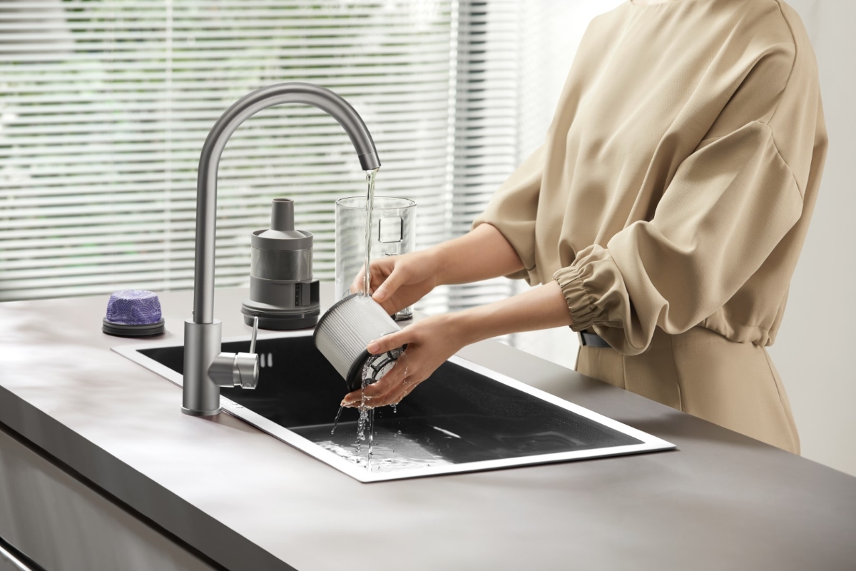 Close up of a person washing the filter of DREAME Z30 STICK VACUUM CLEANER under running water