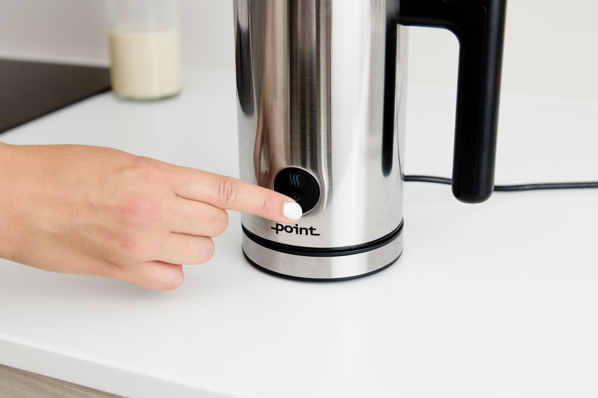 A person pressing the adjustment button on the POINT POMF17SS milk frother