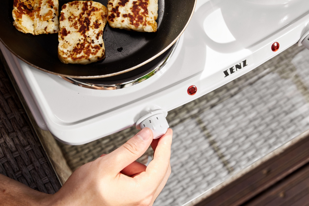 A close up of a person adjusting the temperature on the SENZ SE202D double cooktop