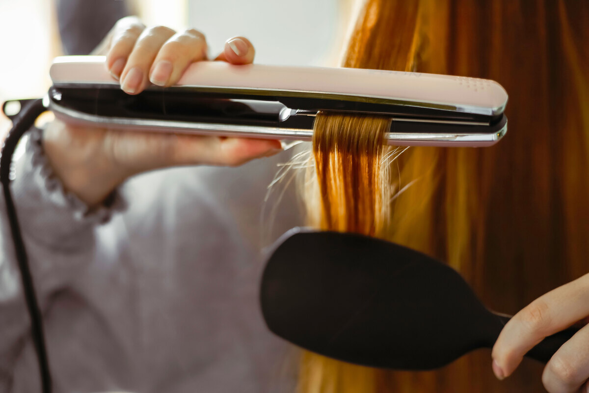 Woman straightening long hair with the help of a brush