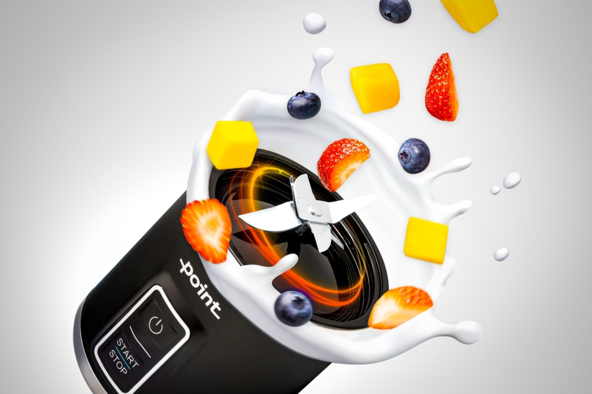 POINT POSB5000 RECHARGABLE SPORT BLENDER A black Point rechargeable travel blender's base against a white background and its steel blades spinning with some milk splash and berries around the moving blade