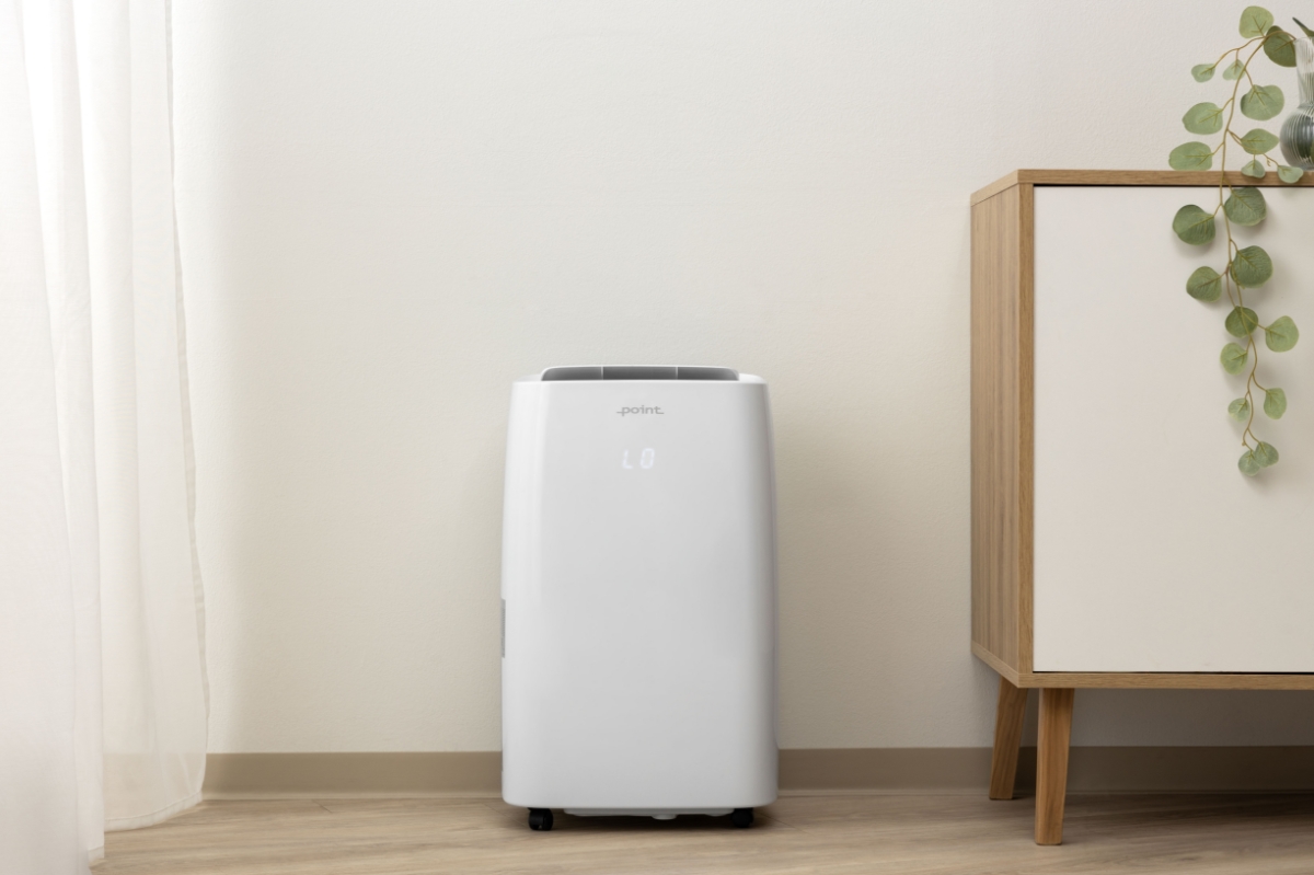 Wide angle image of the POINT PODH3060 DEHUMIDIFIER against a beige wall and a console