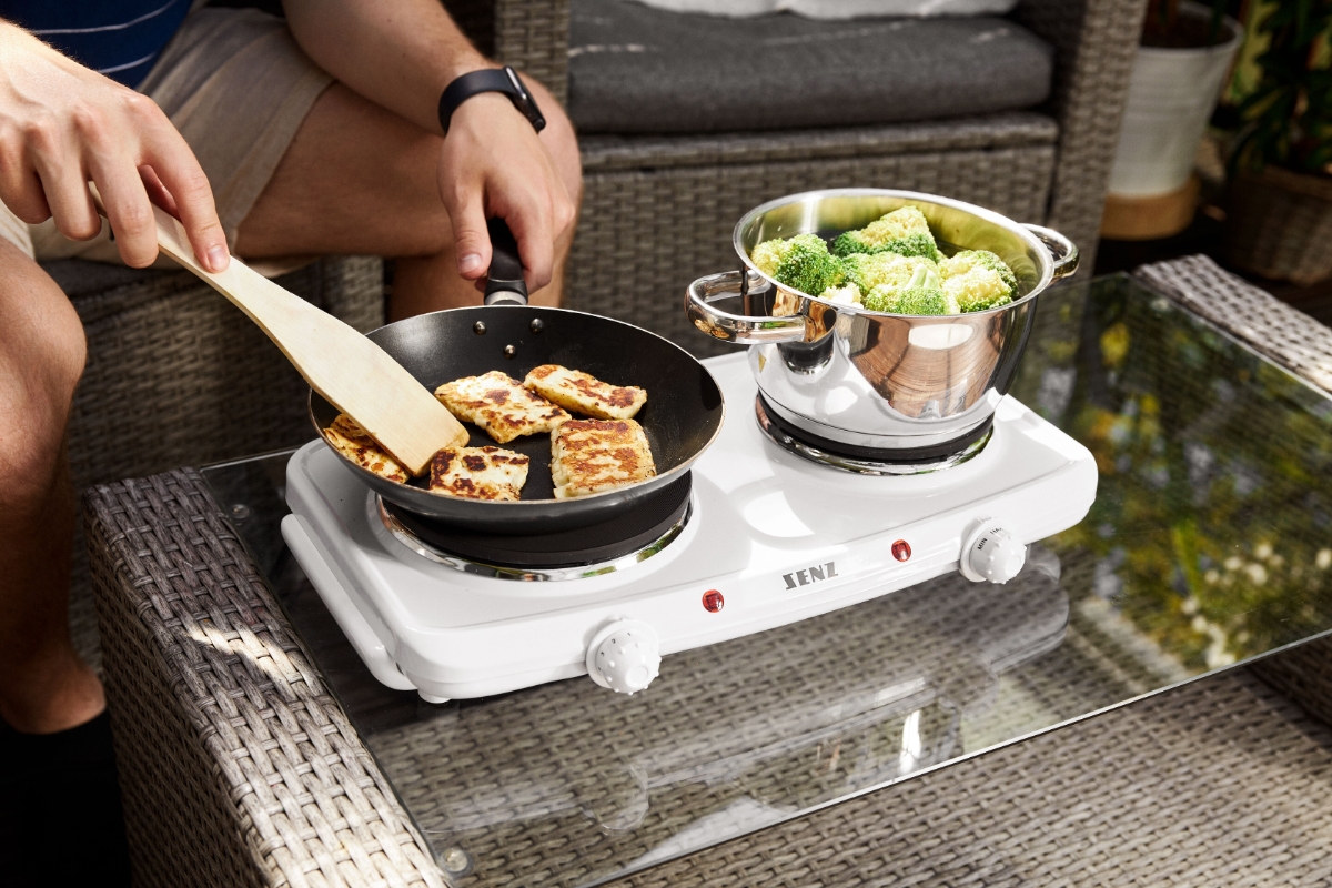 A person cooking halloumi in a cooking pan and broccoli in a pot on the SENZ SE202D double cooktop