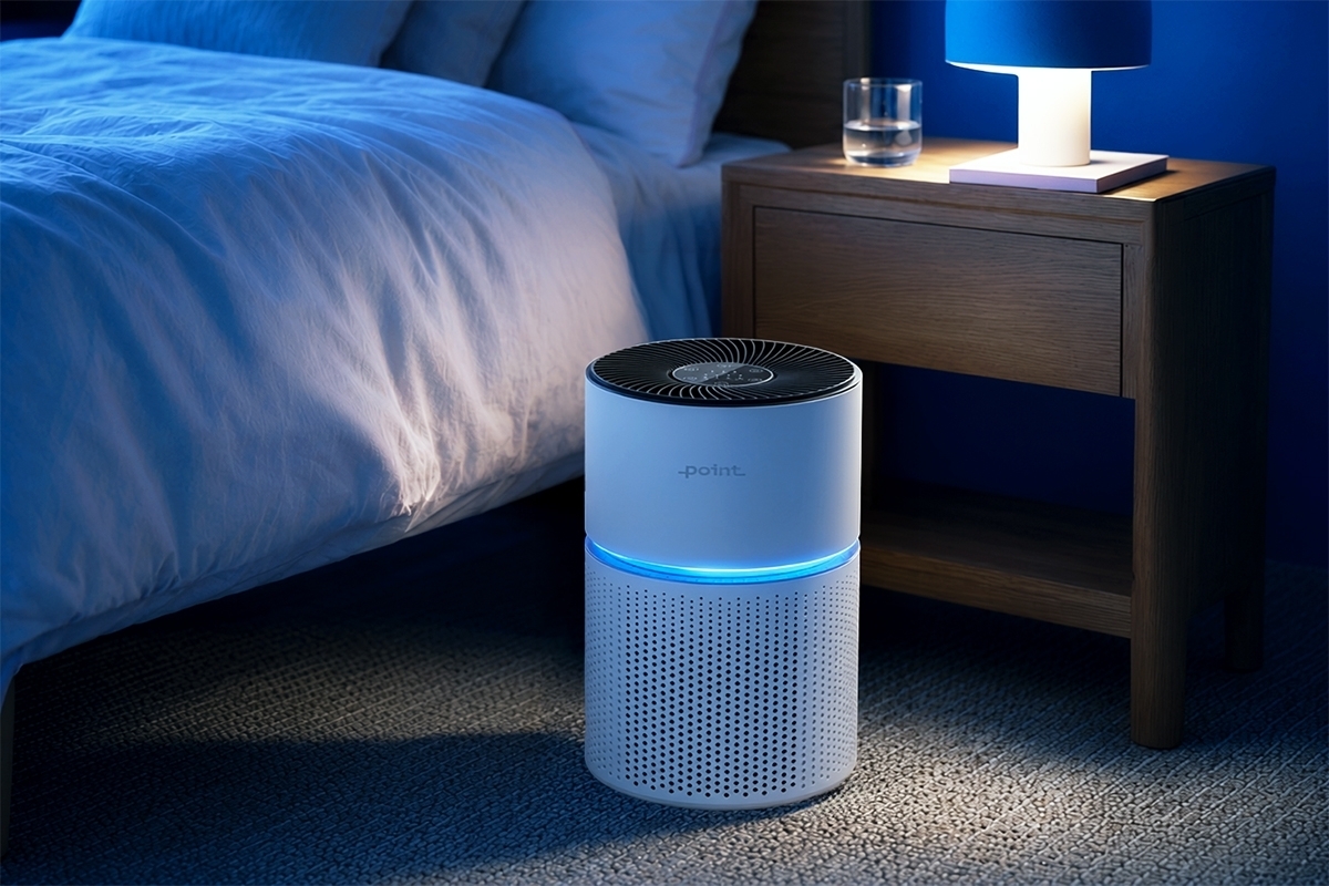 POINT POAP220 AIR PURIFIER A white Point POAP220 air purifier in a dark bedroom next to a bed on the floor with a tiny night light behind the product and blue light coming out of the purifier
