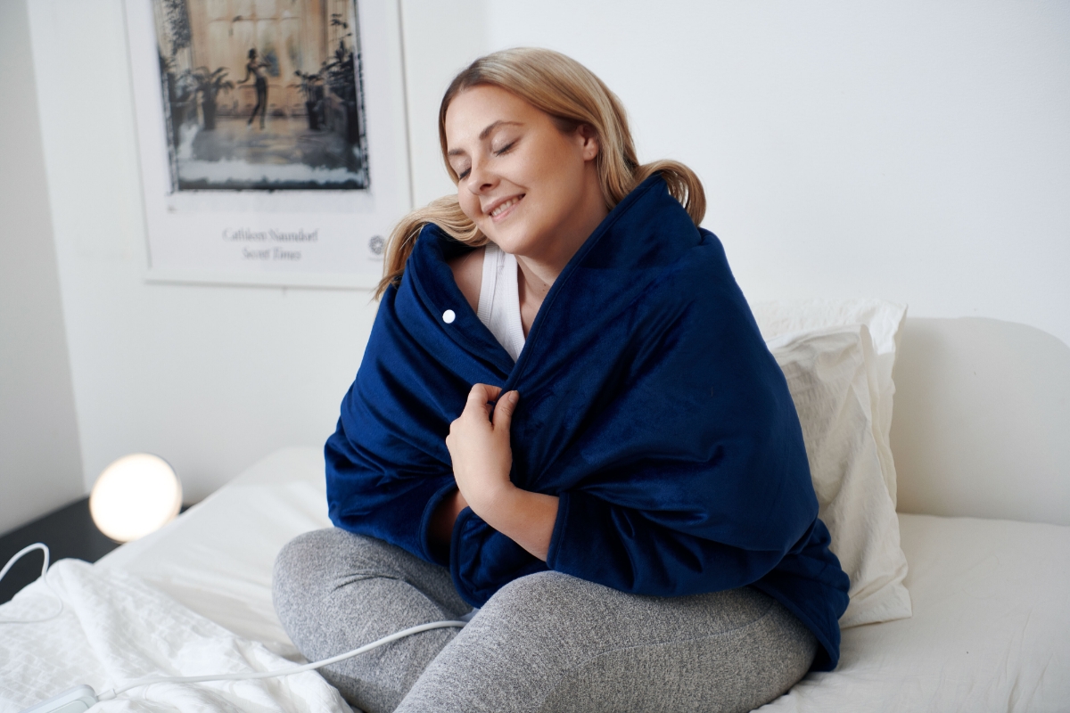 A person snuggling inside the POINT HEAT HUG HEATING CAPE