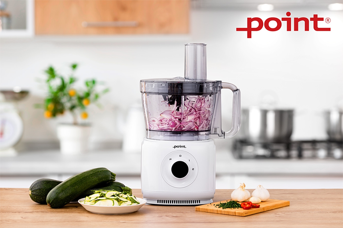 Wide angle image of POINT POFP5000 FOOD PROCESSOR on a kitchen counter, red onion inside the processor and a zucchini next to it on the counter